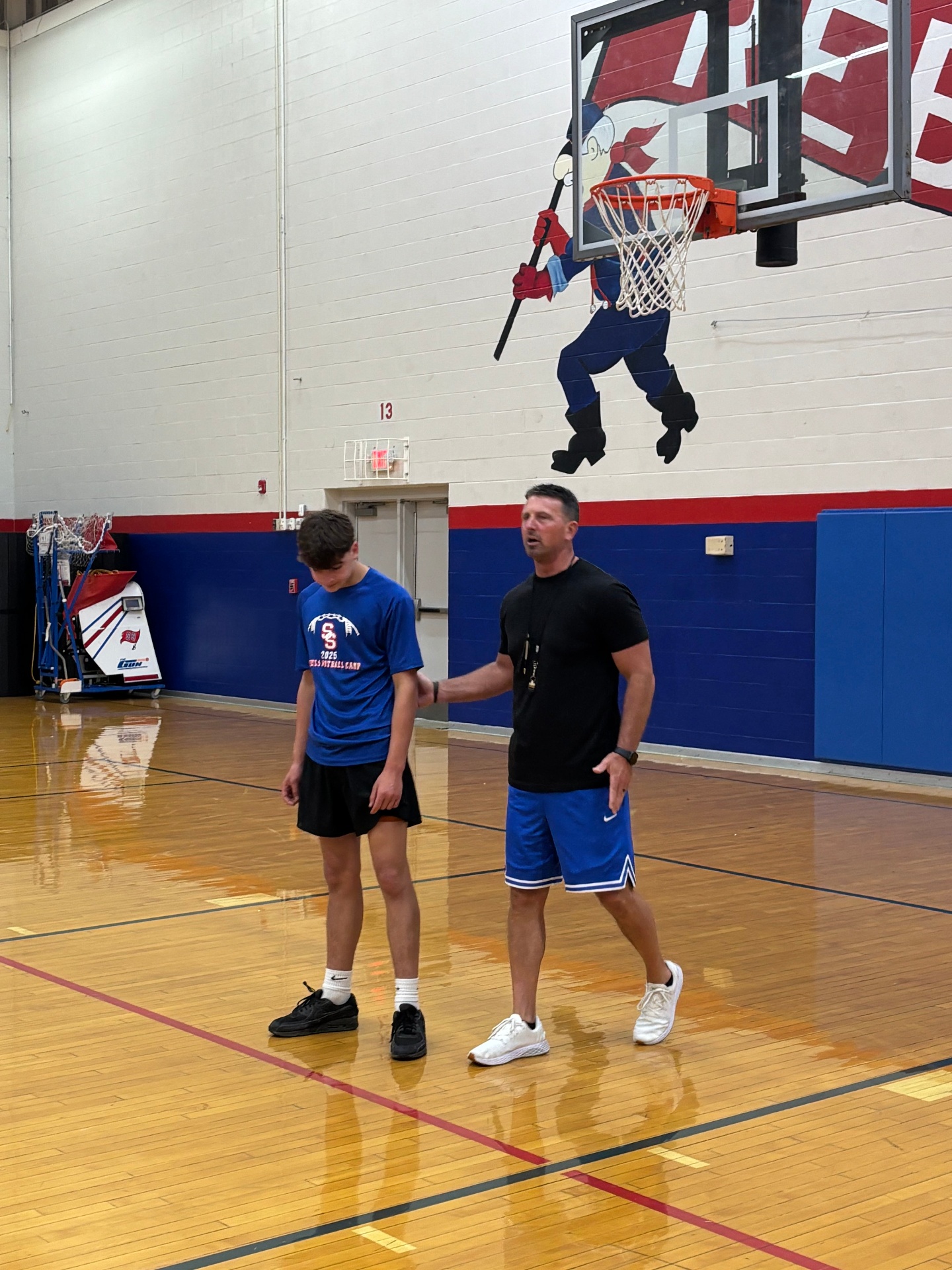 Coach giving feedback under the Rebel mural